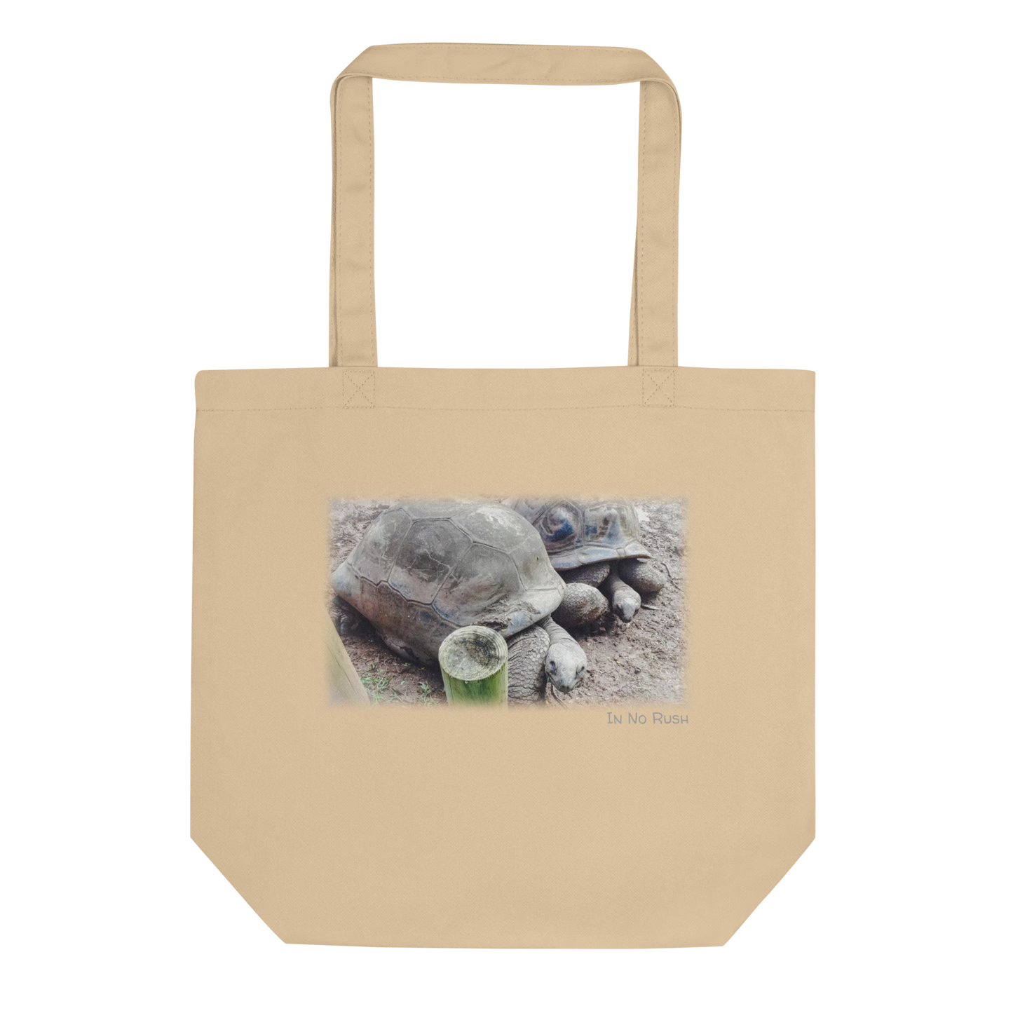 Made from 100% certified organic cotton 3/1 twill. Fabric weight: 8 oz/yd² (272 g/m²). Designed with an open main compartment, 1″ wide dual straps, and a 30 lb (13.6 kg) weight limit. Finished with a front DTG turtle photo print and the phrase “In No Rush.”
