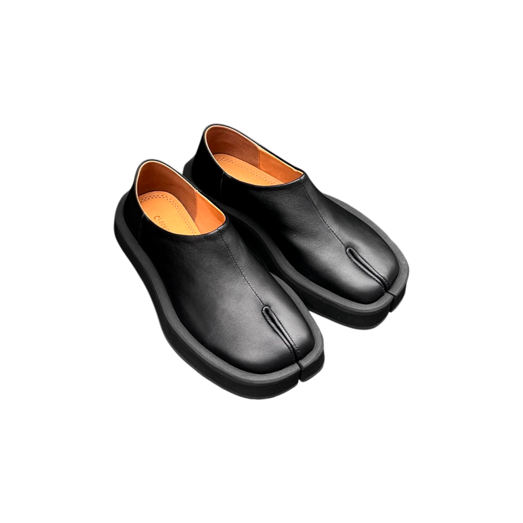 Pair of black leather shoes with orange lining on a white background