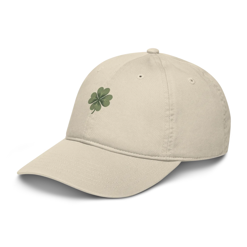 Made from 100% organic cotton in 3/1 twill. Fabric weight: 8 oz/yd² (271 g/m²). Designed as an unstructured 6-panel cap with a low profile, curved visor, matching sewn eyelets, and a self-fabric adjustable closure with a brass slider and hidden tuck-in. Finished with a muted green four-leaf clover print on the front.