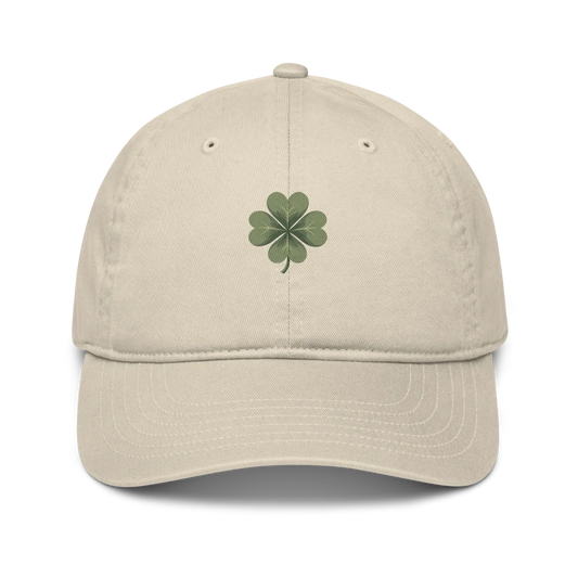 Made from 100% organic cotton in 3/1 twill. Fabric weight: 8 oz/yd² (271 g/m²). Designed as an unstructured 6-panel cap with a low profile, curved visor, matching sewn eyelets, and a self-fabric adjustable closure with a brass slider and hidden tuck-in. Finished with a muted green four-leaf clover print on the front.