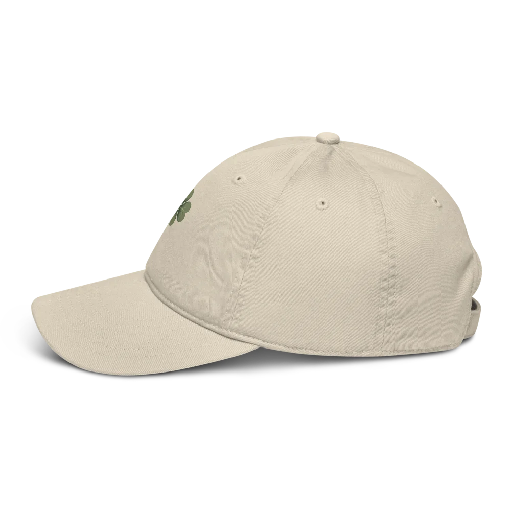 Made from 100% organic cotton in 3/1 twill. Fabric weight: 8 oz/yd² (271 g/m²). Designed as an unstructured 6-panel cap with a low profile, curved visor, matching sewn eyelets, and a self-fabric adjustable closure with a brass slider and hidden tuck-in. Finished with a muted green four-leaf clover print on the front.