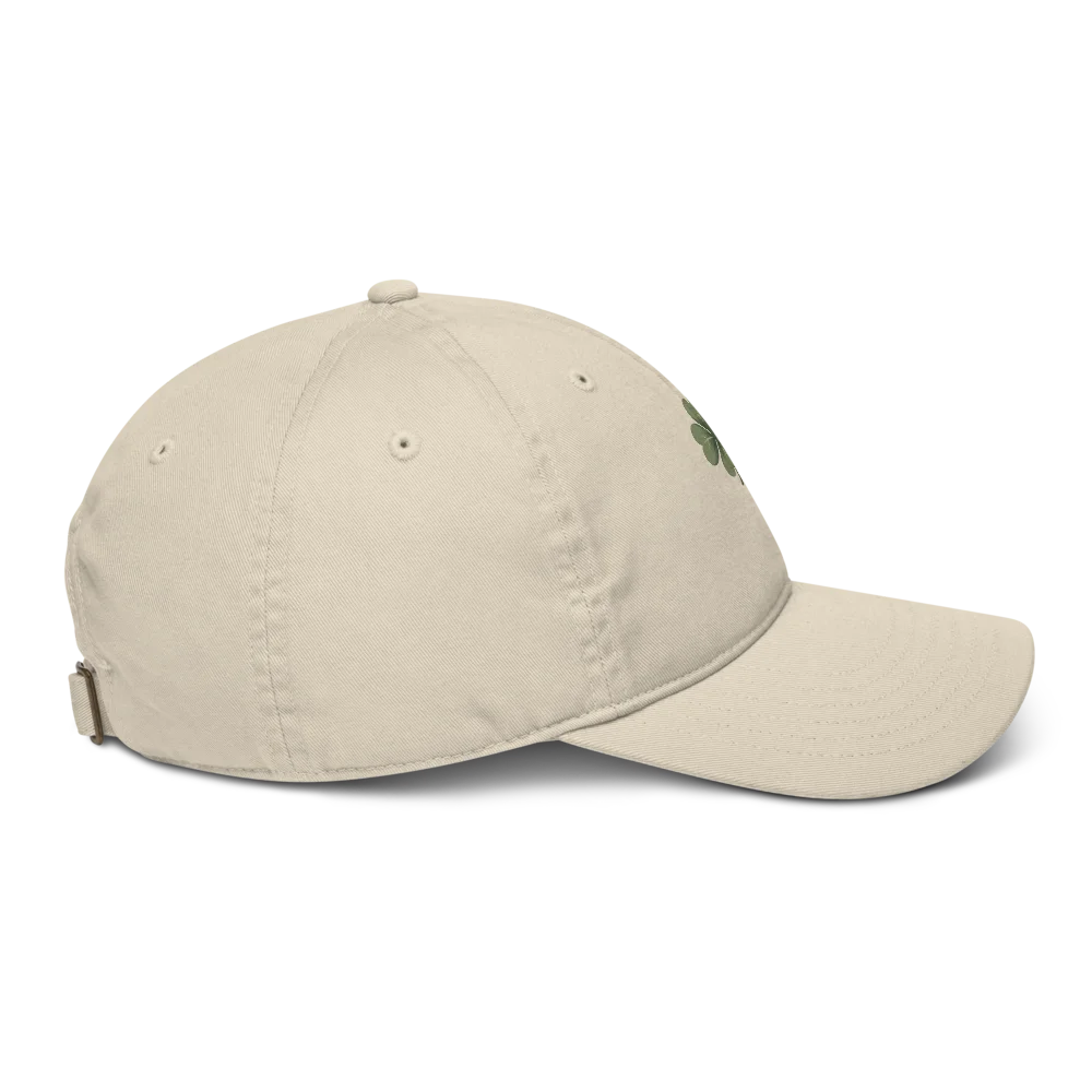 Made from 100% organic cotton in 3/1 twill. Fabric weight: 8 oz/yd² (271 g/m²). Designed as an unstructured 6-panel cap with a low profile, curved visor, matching sewn eyelets, and a self-fabric adjustable closure with a brass slider and hidden tuck-in. Finished with a muted green four-leaf clover print on the front.