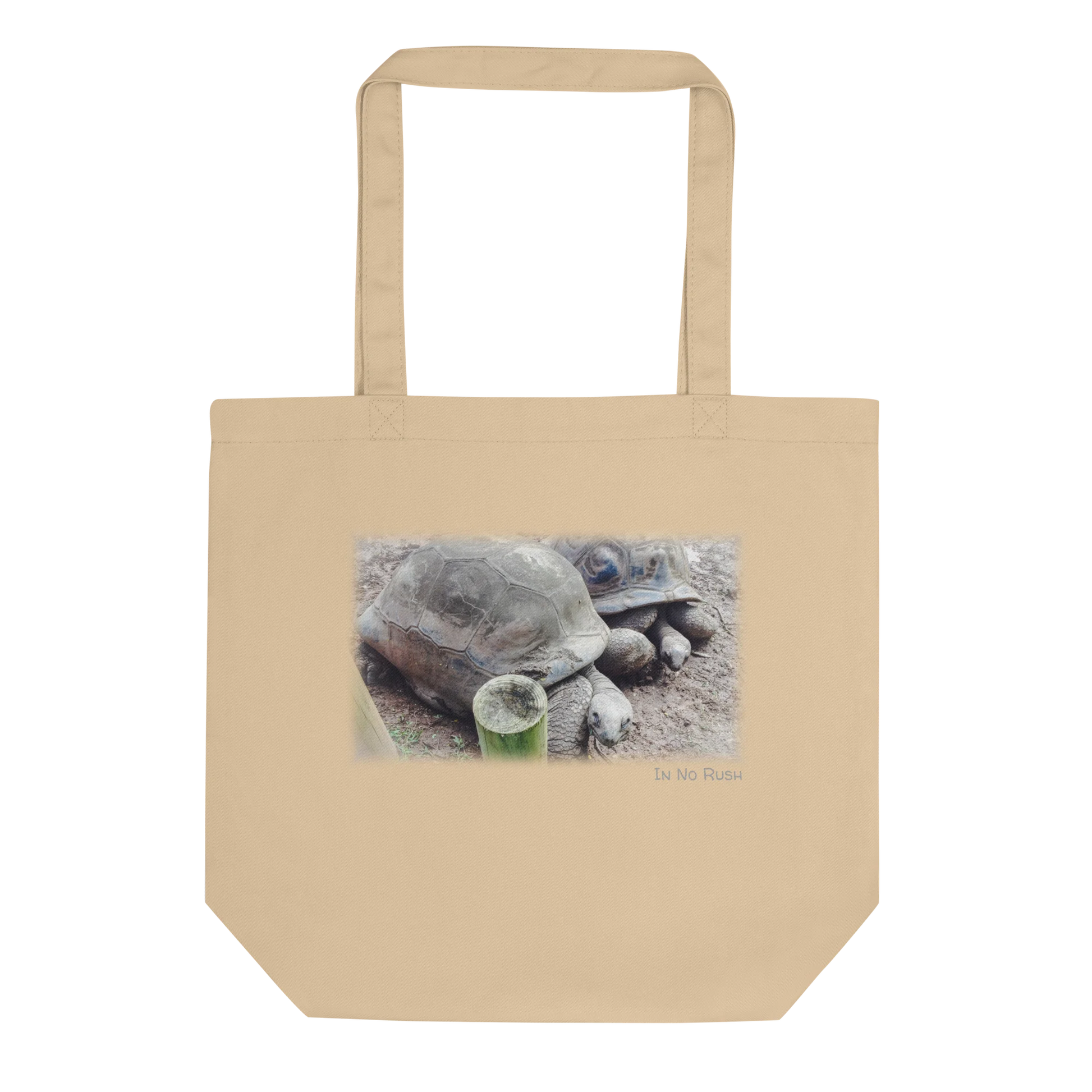 Made from 100% certified organic cotton 3/1 twill. Fabric weight: 8 oz/yd² (272 g/m²). Designed with an open main compartment, 1″ wide dual straps, and a 30 lb (13.6 kg) weight limit. Finished with a front DTG turtle photo print and the phrase “In No Rush.”